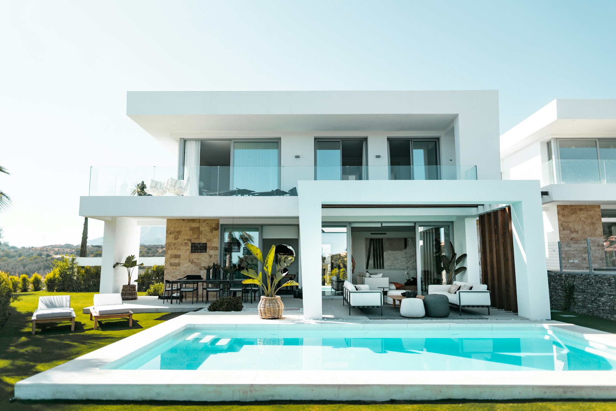 Contemporary coastal home with warm stone, a garden and a pool